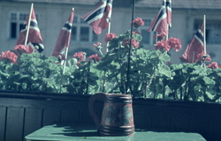 Balkong pyntet med blomster og flagg under feiringen av frig