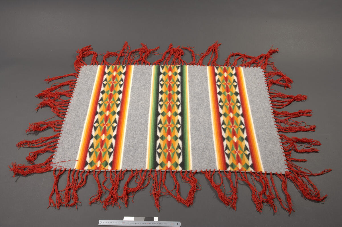 striper med mønster formet av diverse ruder
<TILHORER>Informasjonsetikett "Pendleton Indian Blankets. A warm and colorful heritage" fra produsent Pendelton Woolen Mills i Portland, Oregon</TILHORER>