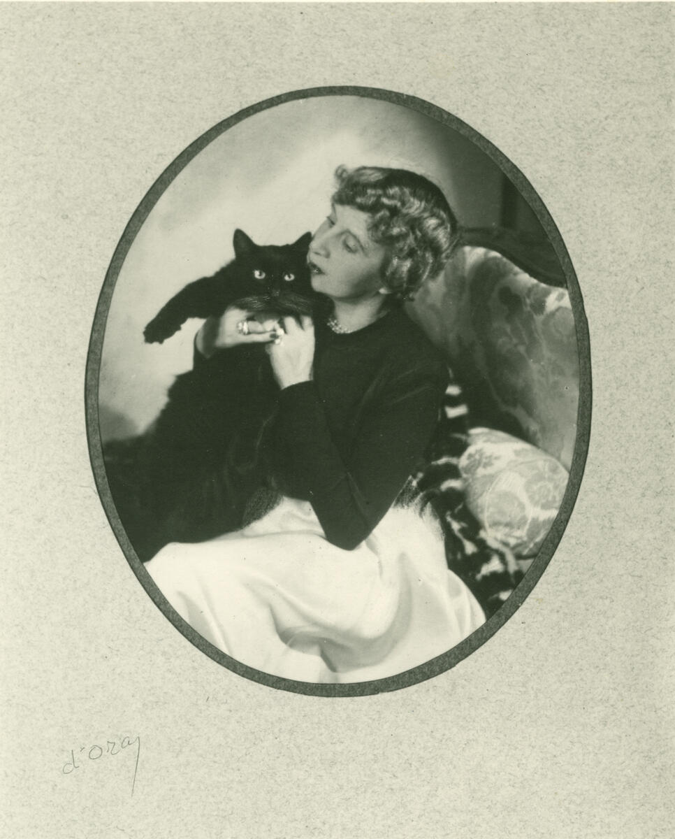 En kvinne med krøllete hår sitter med en sort katt på fanget