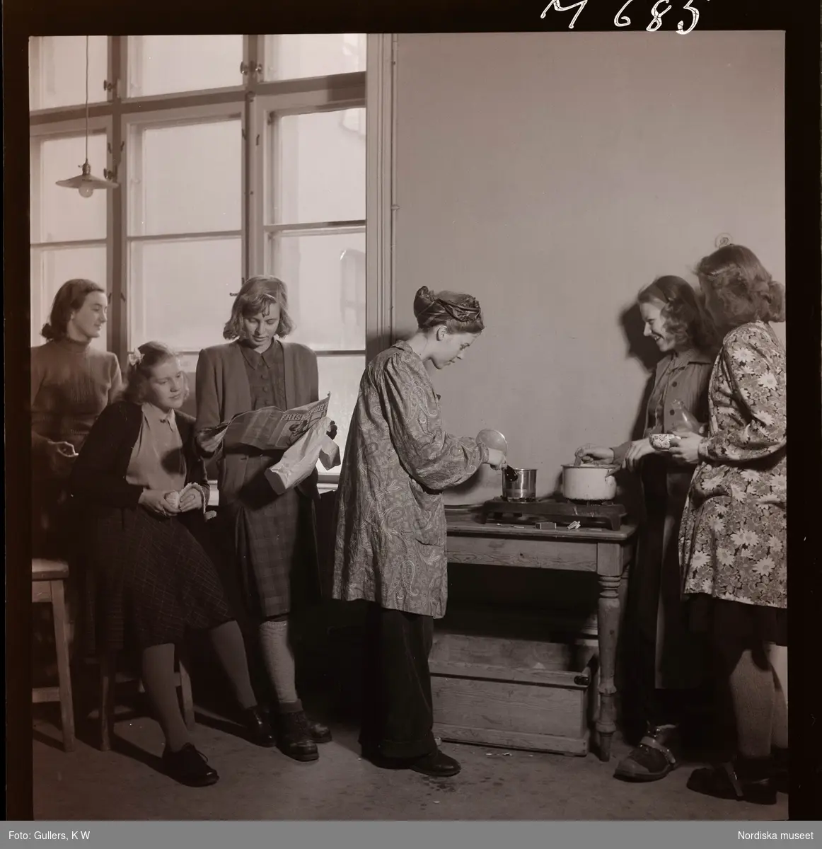 1677 Konstfackskolan. Lunchpaus. Kvinnliga elever värmer mat på kokplatta.
