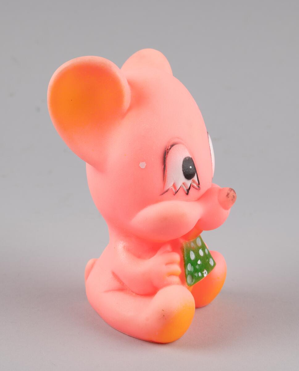 Leketøy av mykplast i form av en sittende, rosa mus som spiser en grønn ost med hvite prikker.