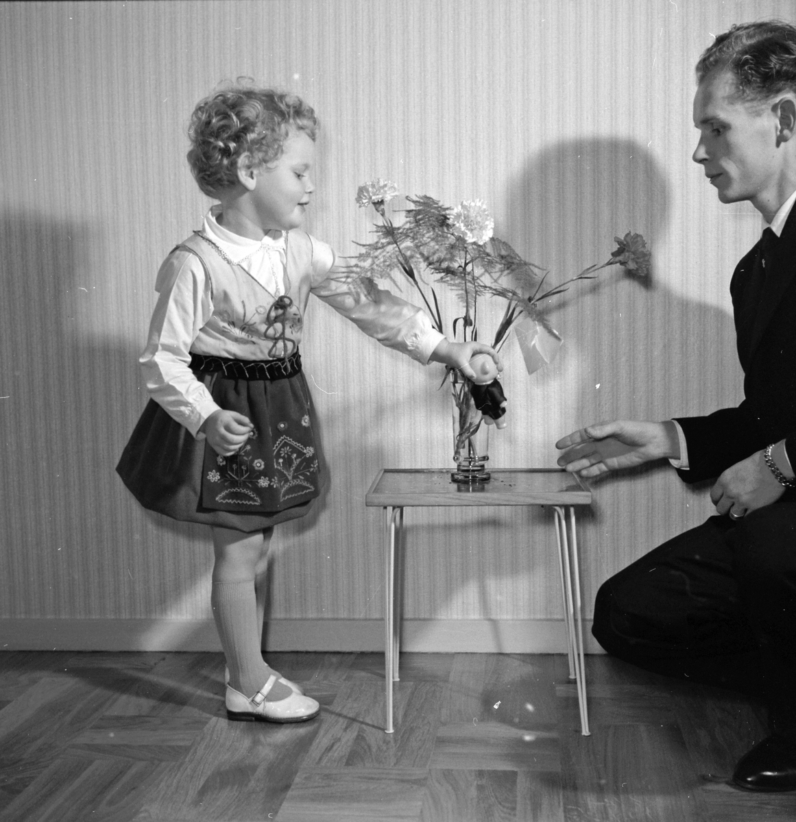Familjen Göran Mårtensson, en liten flicka i finkläder leker med sin pappa Göran