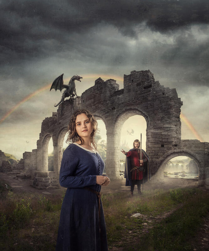 Domkirkeruinene med en drage på toppen. Jente i blå kjole i forgrunnen. Mann med sverd og krone foran ruinene. Fantasylandskap med fossefall, trær og slott skimtes bak ruinene. Mørke skyer på himmelen med en regnbue.