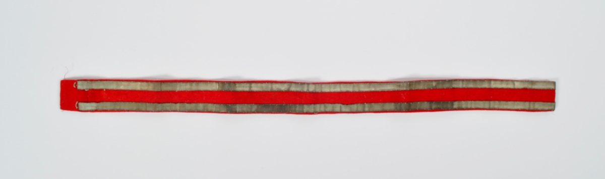 Rødt belte i ullstoff med  to langsgående, ripsvevde metallbånd og to metallhekter.