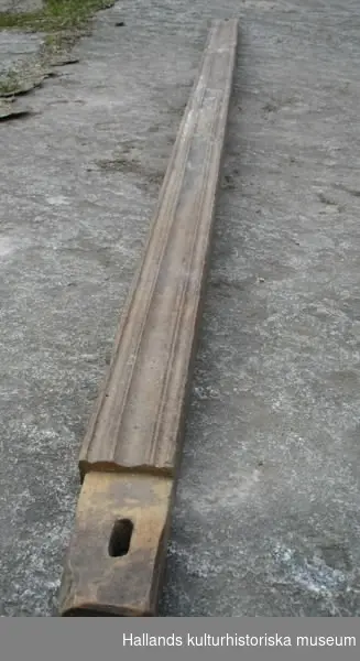Delar till vävstol. Trä, smidda detaljer. a) Trä, metall, snidad, smidda detaljer, kugghjul i ena änden. Spännhandtag. Diameter: 28 cm, längd: 129 cm.
 b) Trä, snidad. Bredd: 10 cm, längd: 57 cm, höjd: 6 cm. 
c) Trä, snidad. Diameter: 7 cm, längd: 139 cm. 
d) Trä, snidad, profilsågad. Bredd: 7 cm, längd: 155 cm, höjd: 6 cm.
 e) Trä, snidad, den del tramorna är fästade vid. Hål för f) och vid mitten även hål i bägge ändar. Bredd: 7 cm, längd: 133 cm, höjd: 6 cm. 
f) Plugg med hål. Trä, snidad, sitter i e), samma som g). Bredd: 5 cm, längd: 18 cm, höjd: 2 cm.
g) Plugg med hål. Trä, snidad, sitter i e), samma som f). Bredd: 5 cm, längd 18 cm, höjd: 2 cm. 
h )Trä, snidad. Bredd: 5 cm, längd: 143 cm, höjd: 3 cm.
i) Trä, snidad, samma typ av föremål som b), samma funktion. Bredd: 10 cm, längd: 56 cm, höjd: 5 cm. 
j) Trä, snidad. Sittbräda till vävstol, kvadratiska hål vid kortsidorna. Bredd: 24 cm, längd: 142 cm, höjd: 2 cm. 
k) Trä, snidad, borrade hål i ena änden, den del varpen viras upp från. Diameter: 21 cm, längd: 156 cm. 
l) Trä, snidad, profilsågad, hål i bägge ändar. Bredd: 7 cm, längd: 146 cm, höjd: 3 cm.
m) Trä, snidad, sidostycke till vävstol. Bredd: 7 cm, längd: 163 cm, höjd: 143 cm. 
n) Trä, snidad, sidostycke till vävstol. Bredd: 7 cm, längd: 162 cm, höjd: 142 cm.
 o) Trä, snidad. Slagbom till vävstol. Vissa delar ersatta med nyare. Bredd: 4 cm, längd: 137 cm, höjd: 75 cm.
 p) Trä, snidad. Nytillverkad del till vävstol som ersatt en äldre. Diameter: 3 cm, längd: 147 cm.