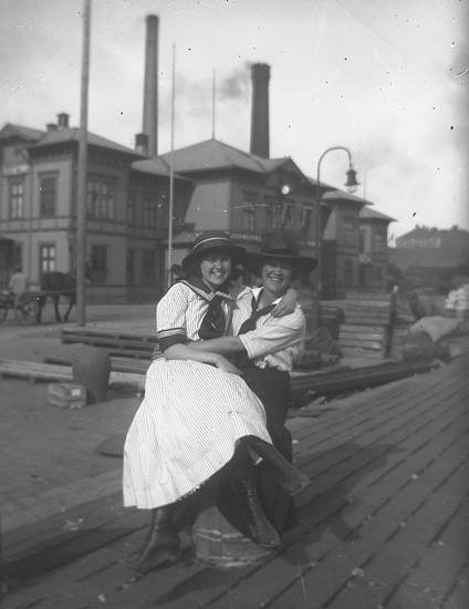 Två glada personer omfamnar varandra framför järnvägsstationen.