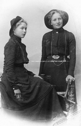 Portrett av to unge kvinner i mørke kjoler.