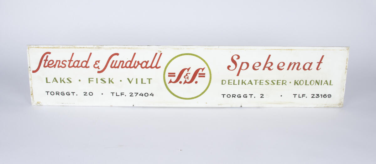 Skilt i hvit farge med rød og grønn skrift for Stenstad & Lundvall spekemat. 