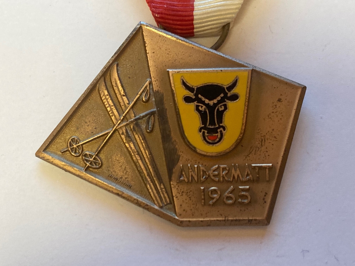 Forsiden av medaljen består av ett par ski med staver til venstre. På høyre side er det avbildet våpenet til kantonen Uri i Sveits med "Andermatt 1965" skrevet under. Våpenet er gult med et oksehode i midten. 