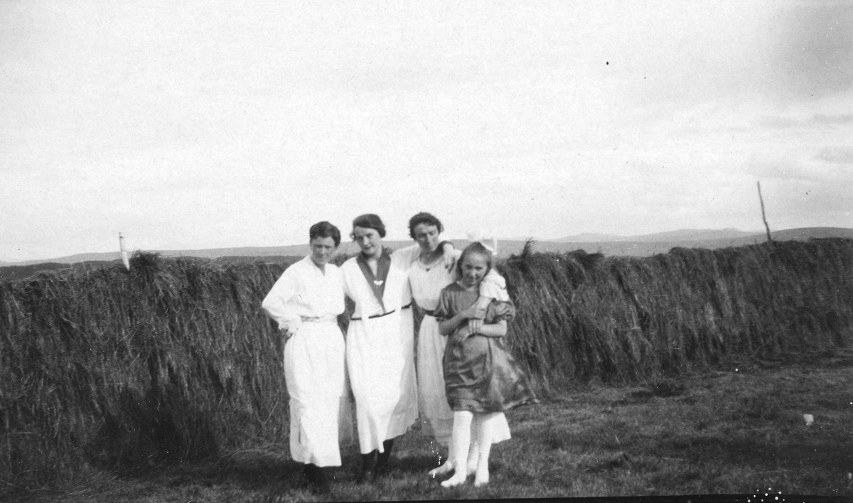 Tre kvinner og ei ung jente står foran ei hesje