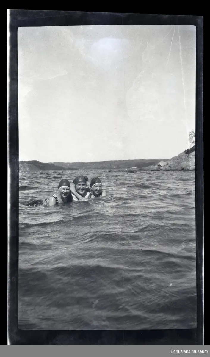 Tre personer badar i havet.