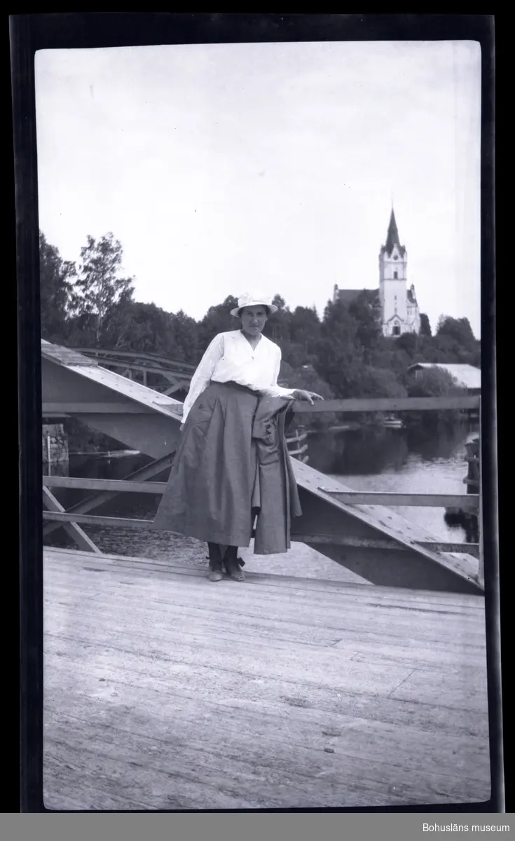Person ståendes på en bro med en kyrka i bakgrunden.