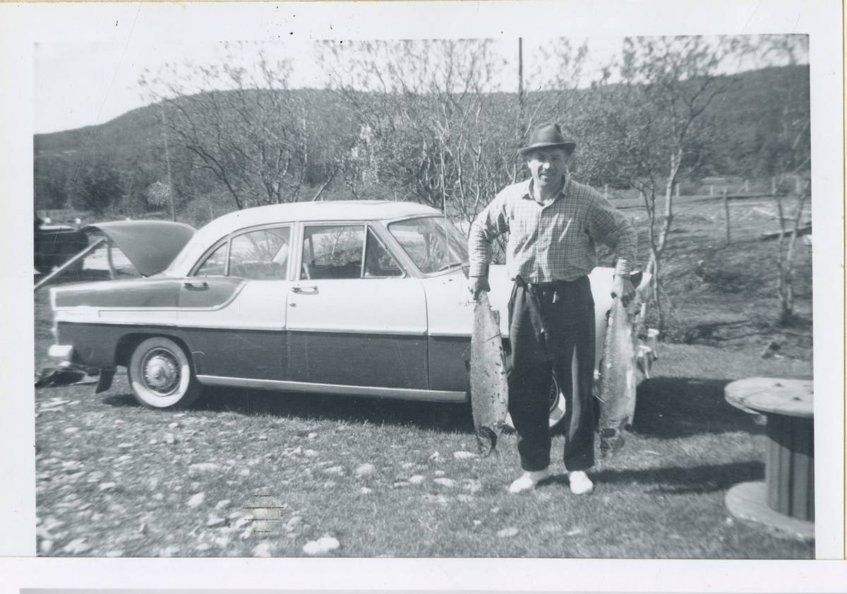 Mann med nyfisket fisk ved pensjonatet/campingplassen i Olderjord.