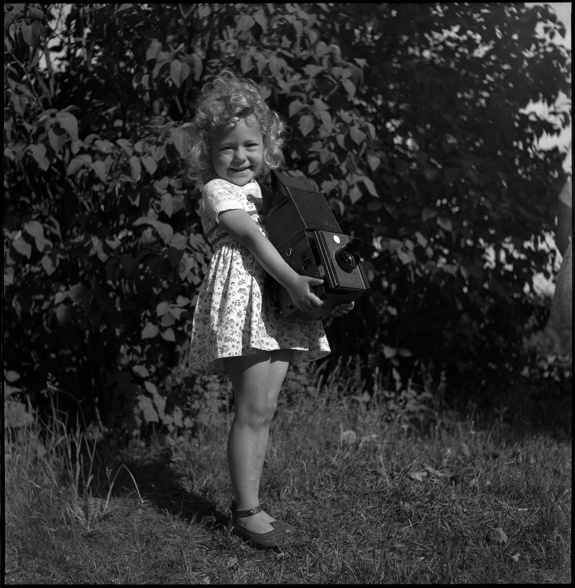 Okänd flicka bär på fotografen Karl Åséns kamera, juni 1957.