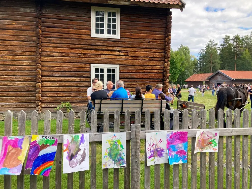 Hest og kjerre under Barnas dag 2022. Barnetegninger i forgrunn på et gjerde.