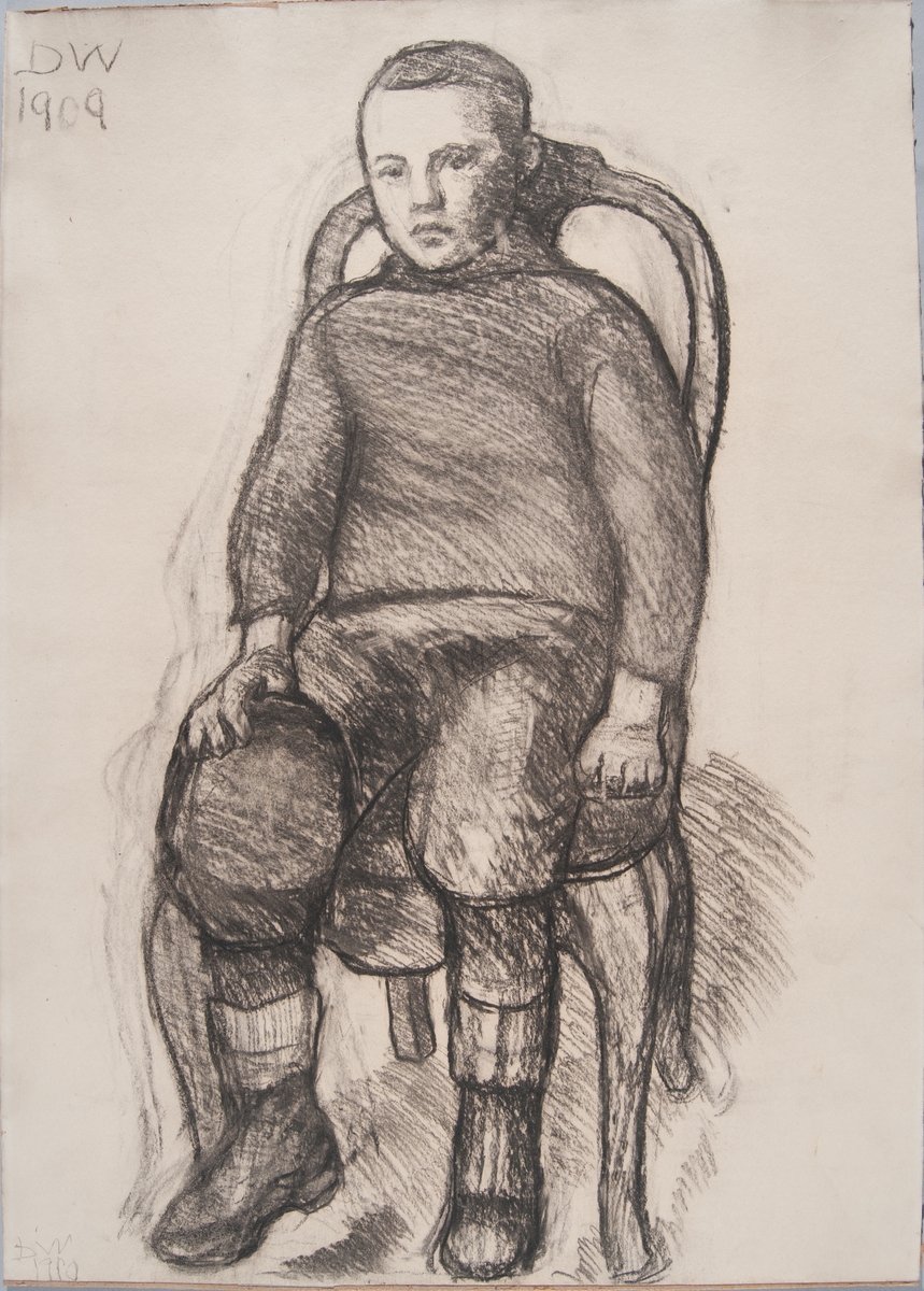 En gutt sittende på en stol en face, støvler og raggsokker, knickers og genser.