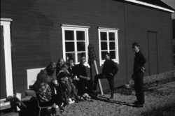 Museet i Ny-Ålesund. Folk utenfor bygning i sola.