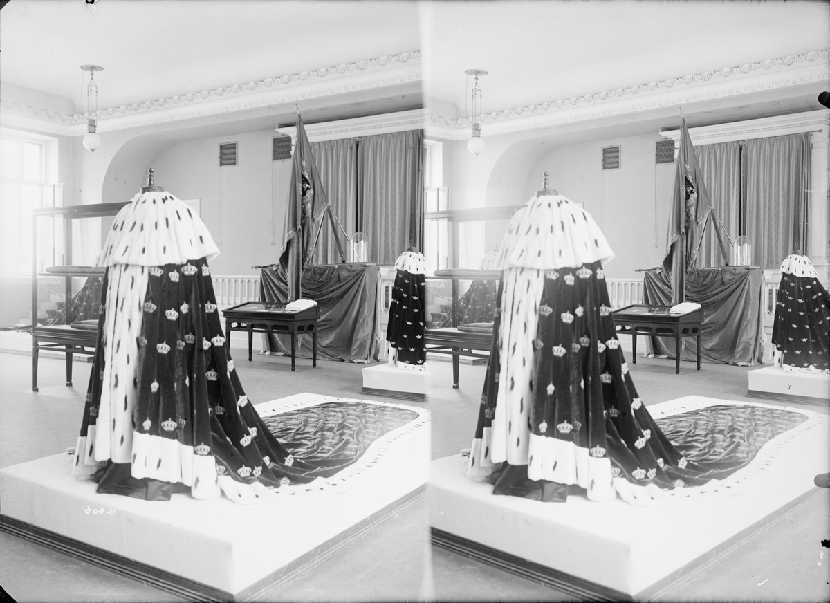Stereofotografi. Kongens kroningskåpe er utstilt sammen med andre gjenstander med forbindelse til kroningen av kong Haakon og dronning Maud i 1906.