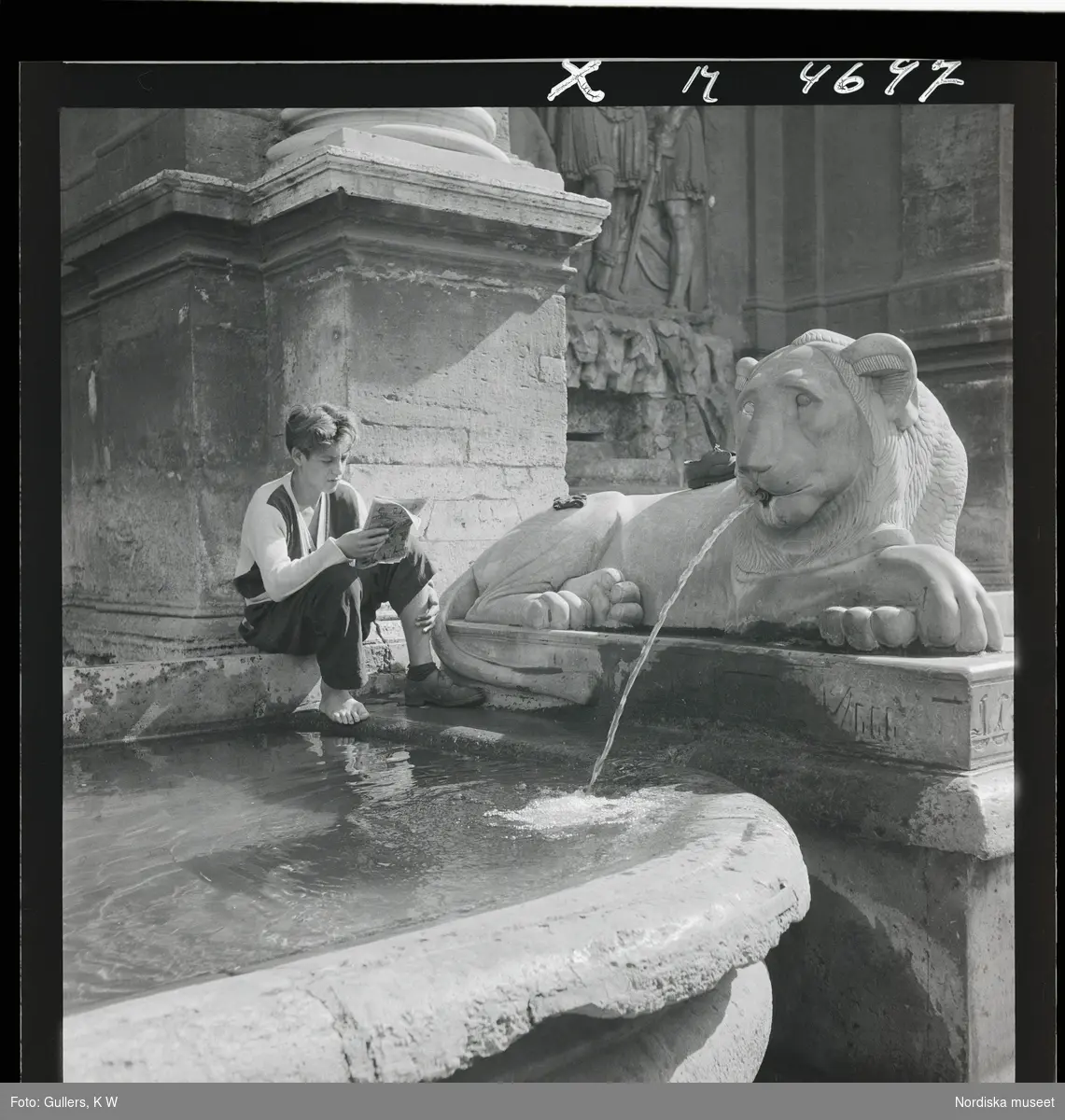1717/A Rom. En ung man sitter och läser vid en fontän i form av lejon.