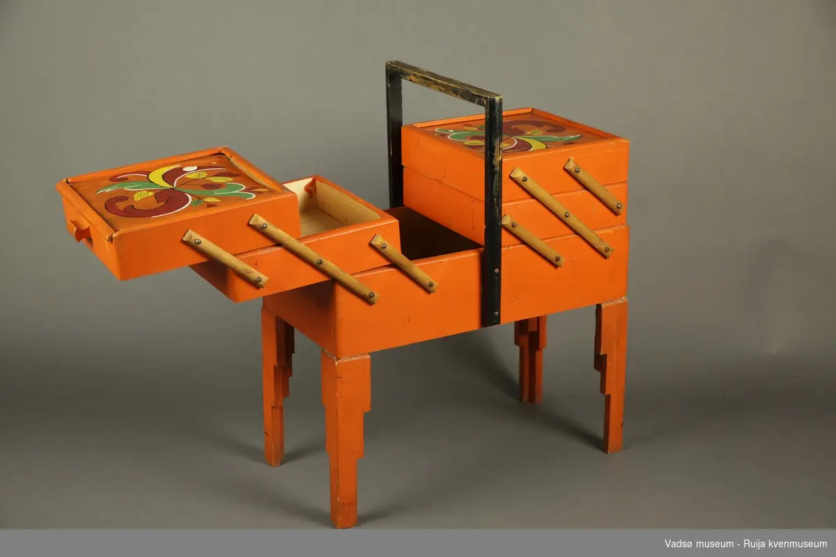 Jfr. Tilvekstprotokoll 1978-1984: Oransjemalt sybord med dekorerte ("rosemalte") lokk. To doble skuffeetasjer og hel skuff nederst. Har manglet ett ben, komplett pr 2022.