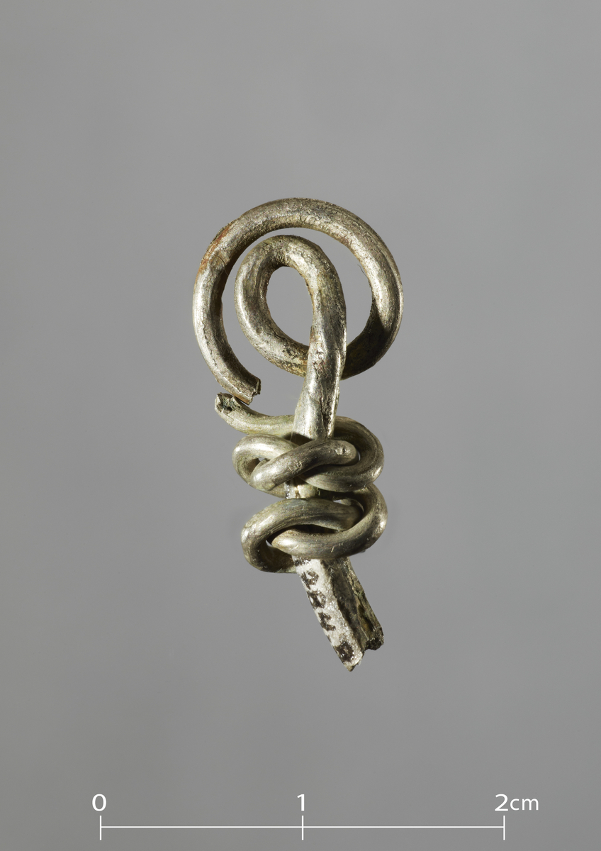Mulig endestykke til sølvring med sølvspiralavslutning. (Mulig fragment av Ts. 11784.7.) Stykkets lengde: 2,4 cm, tykkelse 0,25 cm.