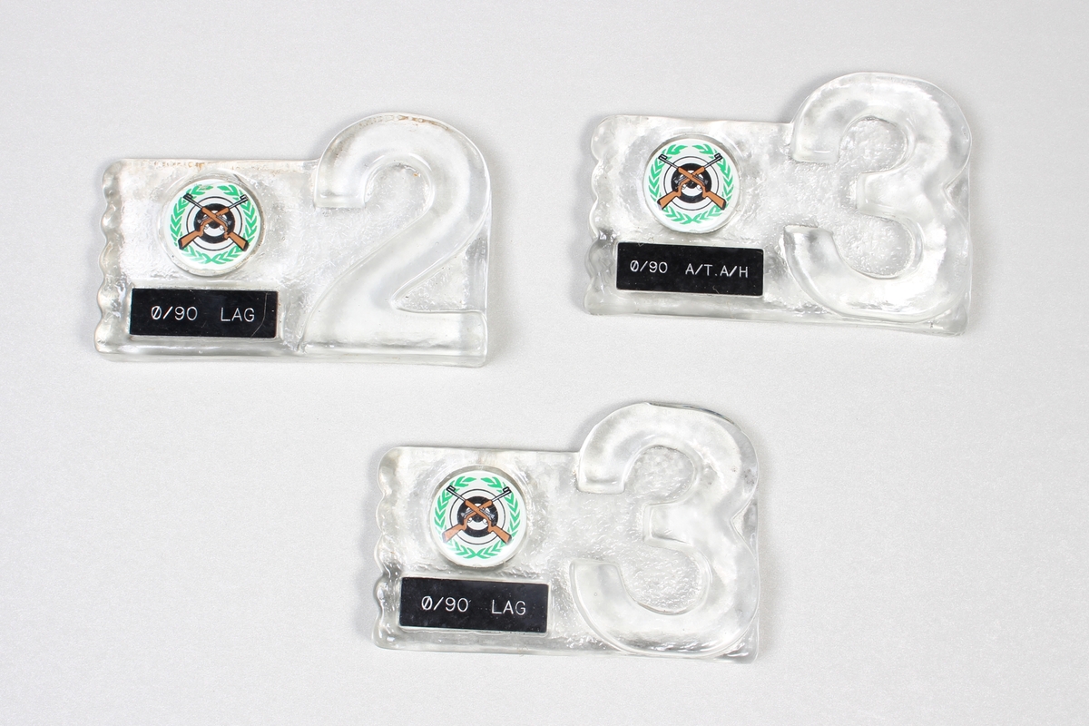 3 stk troféer i presset glass med likt rundt emblem og lite sort skilt.