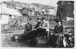 Fire herrer sitter i solen på Sjøvegan i Salangen. Gamle byg