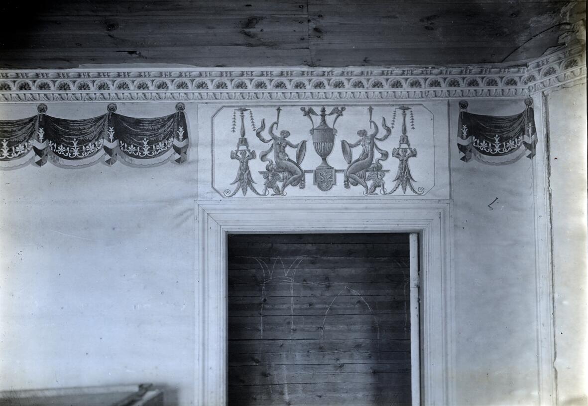Tapetsering i rummet åt trädgården i stora byggnadens övervåning. Denna våning uppges vara byggd år 1802. Papperstapet struken med limfärg i klargult. Taklist av trä, klädd med tre smalt tryckta tapetbårder, den mittersta i grått och gulbrunt, de båda andra enbart grå.
Nedanför på väggen är klistrad en bred utskuren draperibård i mörkblått, rödgult och vitt
hängd i påklistrade rosetter - skuggor och dylikt målat. Dörröverstycket med vit botten och 
figurer i guldgulbrunt. Slät vit bröstpanel i fönsterhöjd, av papper och en bröstlist.     
 Dokumentation  Manne Hofrén.