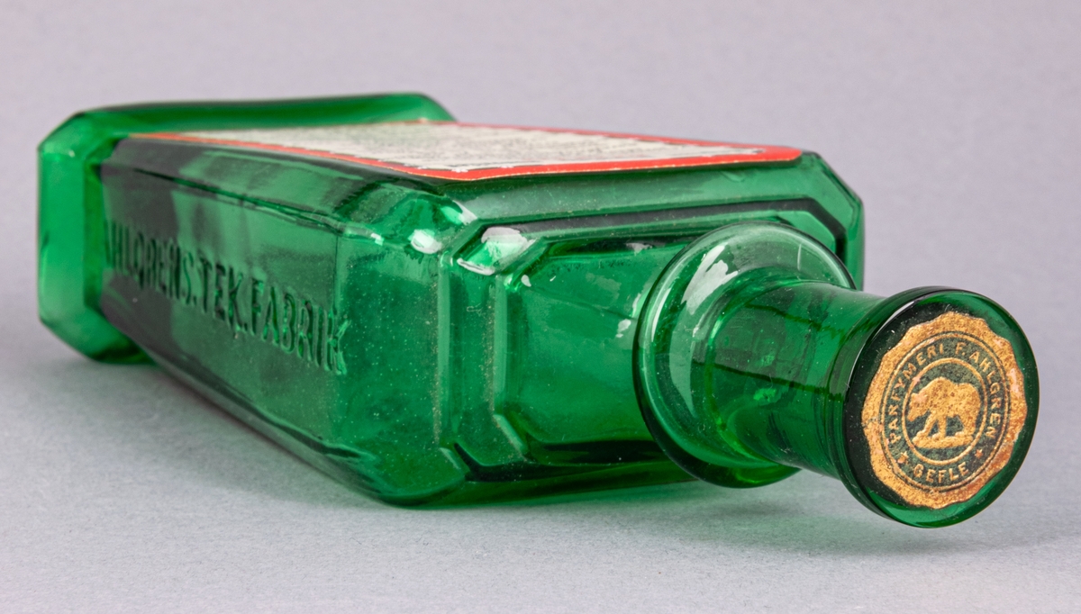 Glasflaska för munvatten, grön, rektangular, med kork. Profilerad skuldra. Etiketter på fram- och baksida. Präglad text på sidorna.
