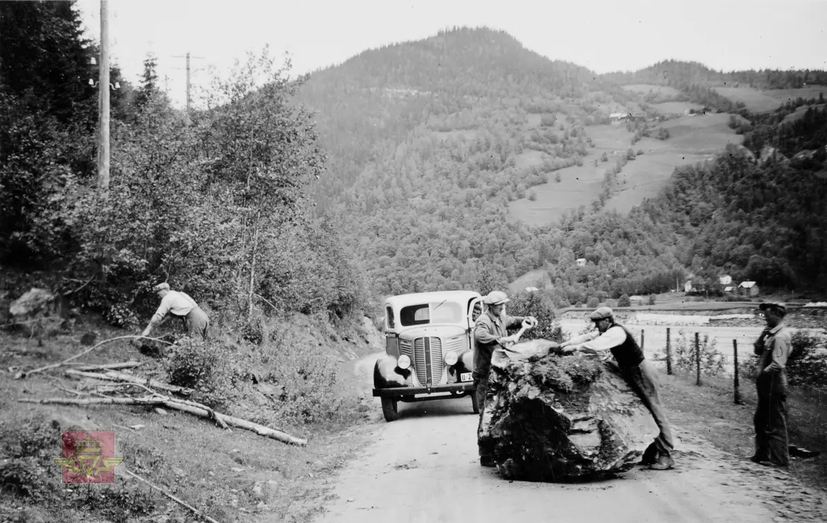 Steinsprang ved Auneberga i daværende Rv.130 (nå Rv.30)  26. juni 1939. 
Vegarbeidere og lastebil bak stor stein på vegen.