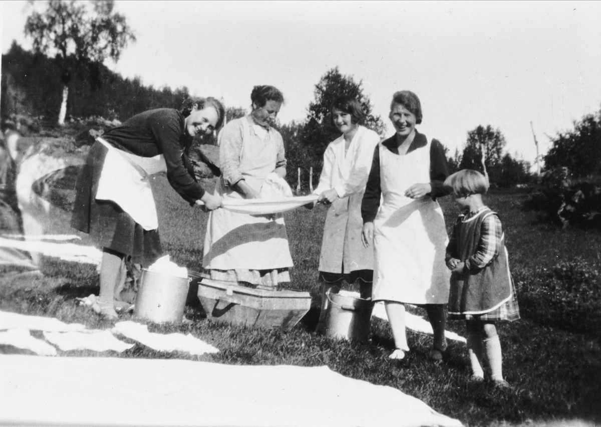 Kvinner strekker klesvask før den blir lagt på bakken til bleking og tørk.