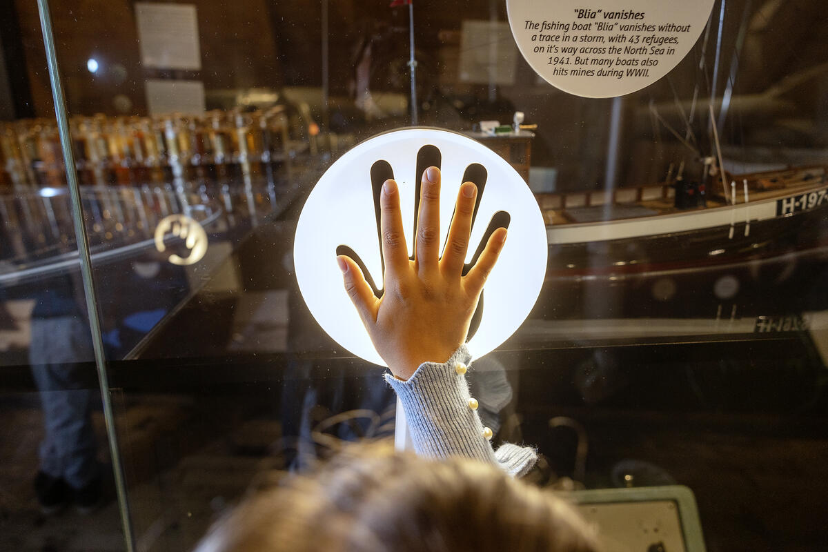 VI ser en barnehånd på en lysende hvit runding, en del av utstillingen i ressurser til låns