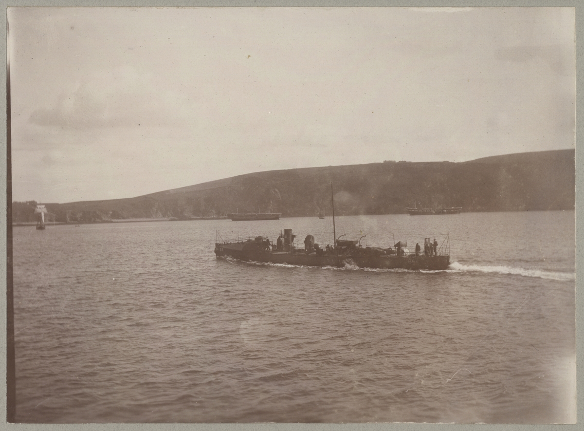 Bilden visar en torpedbåt till havs. I bakgrunden syns två större segelfartyg till ankars utan riggning.