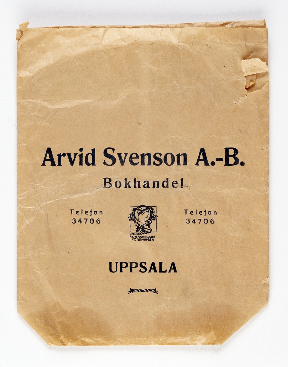 Beige påse med blå tryckt text. "Arvid Svenson A.-B. Bokhandel Uppsala.  På mitten av påsen stämpel med texten "Svenska bokhandlare föreningen."