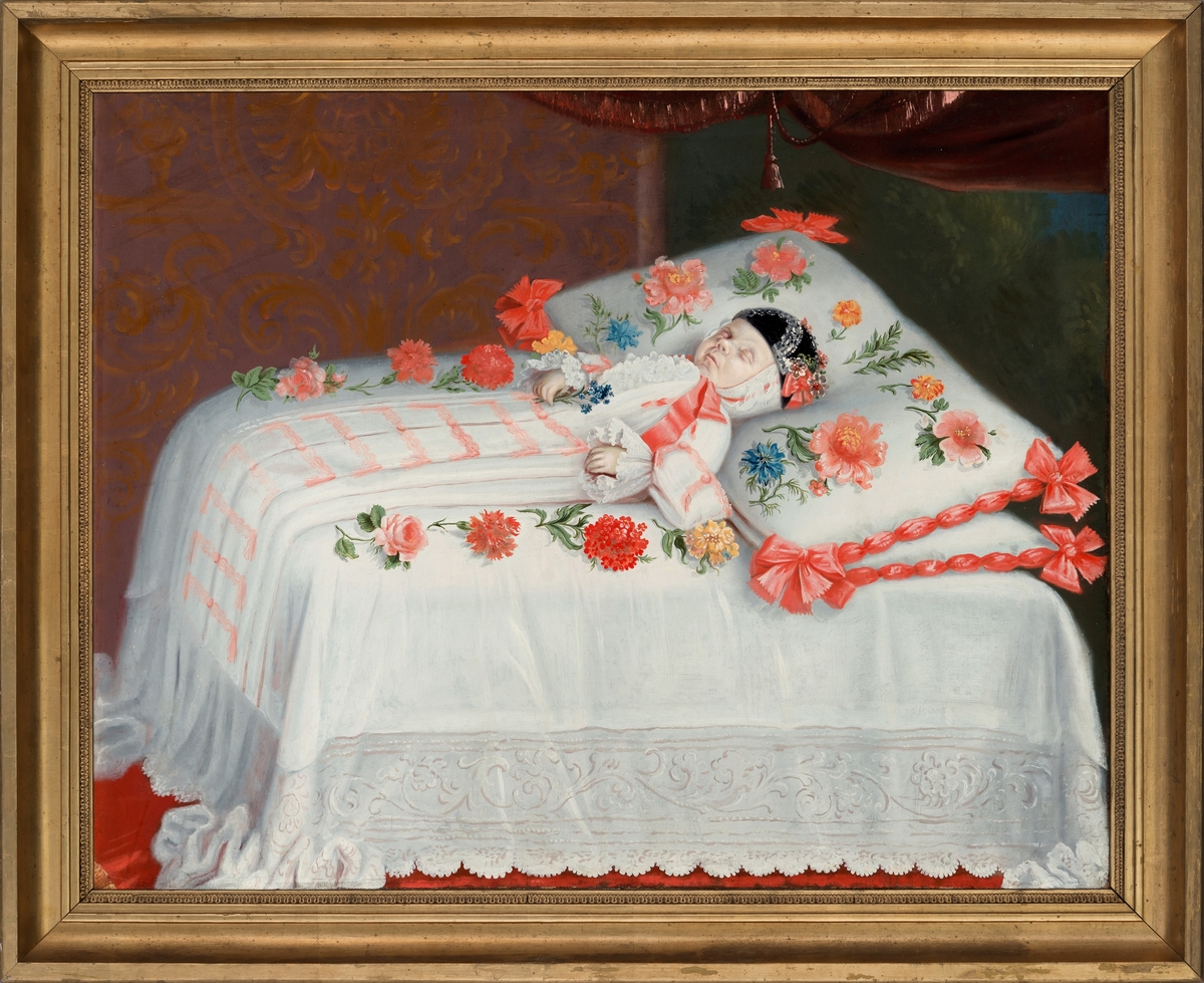 Christopher Wagner. Liggende på en seng med stor pute under hodet, iført sid hvit kjole og sort lue. Omgitt av blomster.