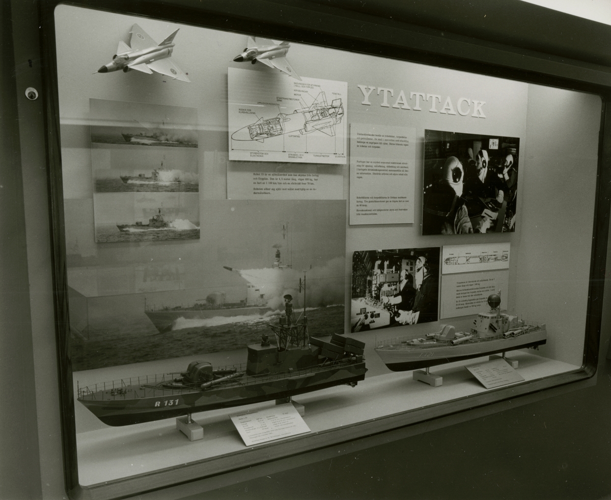 Den permanenta utställningen fotograferad 1987. Monter som handlar om Ytattack. Fotografier och förklarande texter samt fatygmodeller av robotbåten R131 NORRKÖPING och torpedbåtenT121 SPICA. Även två modeller av stridsflygplanet JAS GRIPEN.