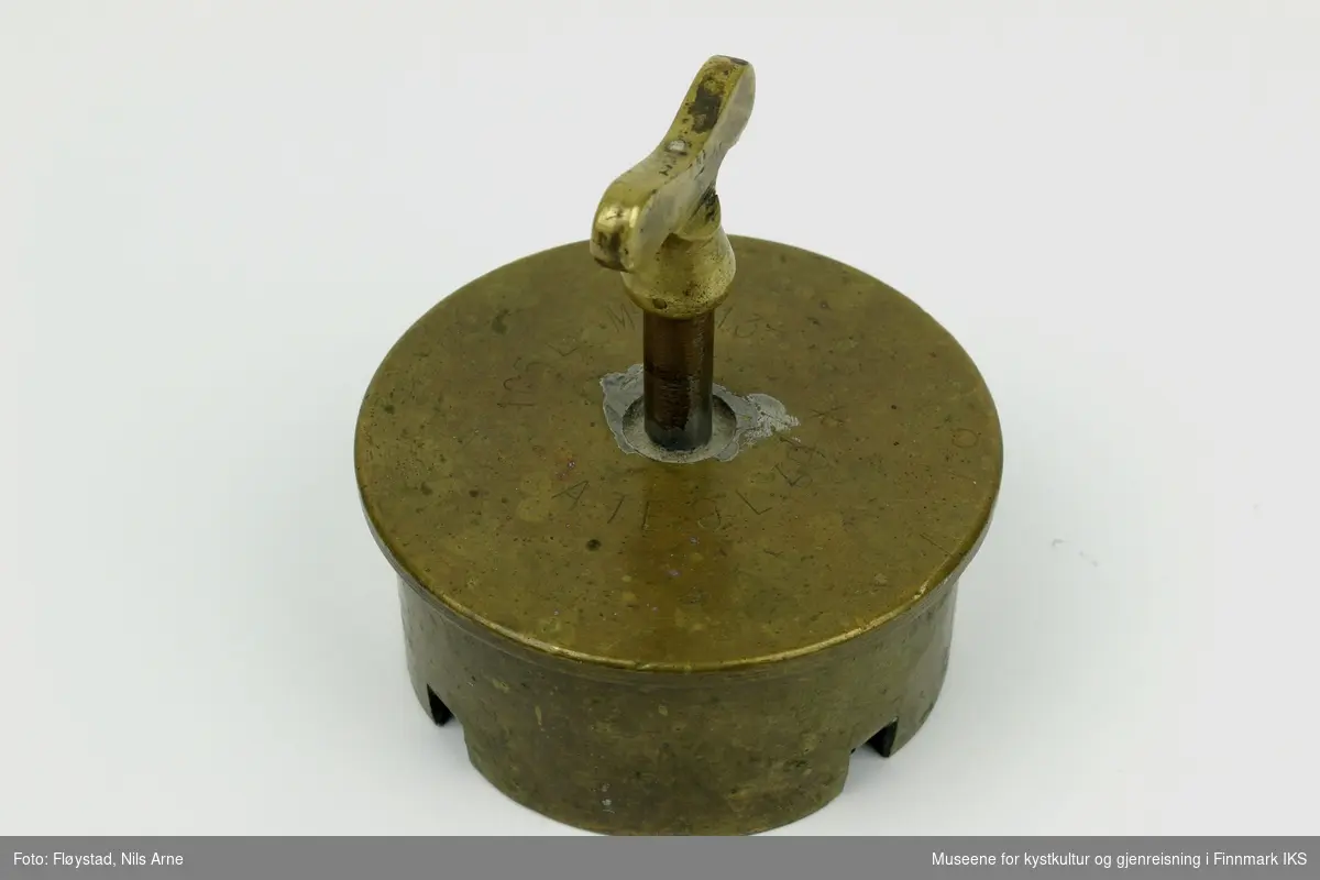 Et kokelodd laget av en 105 millimeter granathylse med en krannøkkel som håndtak. Det er støpt bly på innsiden av hylsen.  

Granathylsen har gravert den franske betegnelsen "105 L Mle 1913" og "ATE 9 L 49 X",  og var ammunisjonstypen til den franske feltkanonen "Canon de 105 L Mle 1913 Schneider" fra 1913. På innsiden av hylsen er det støpt bly.  

Håndtaket er en krannøkkel med spindel og nøkkelformet kranhode.