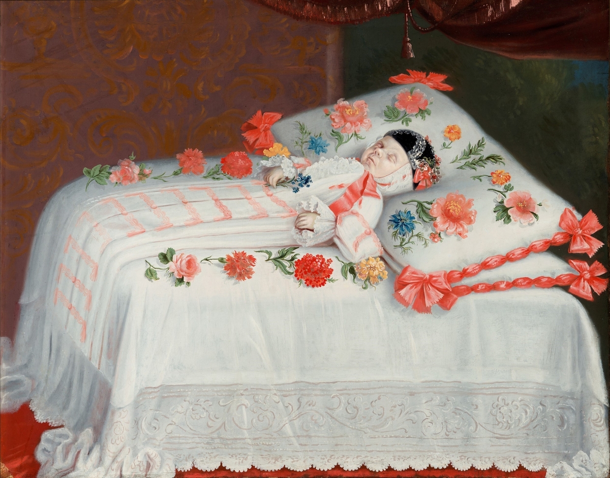 Christopher Wagner. Liggende på en seng med stor pute under hodet, iført sid hvit kjole og sort lue. Omgitt av blomster.