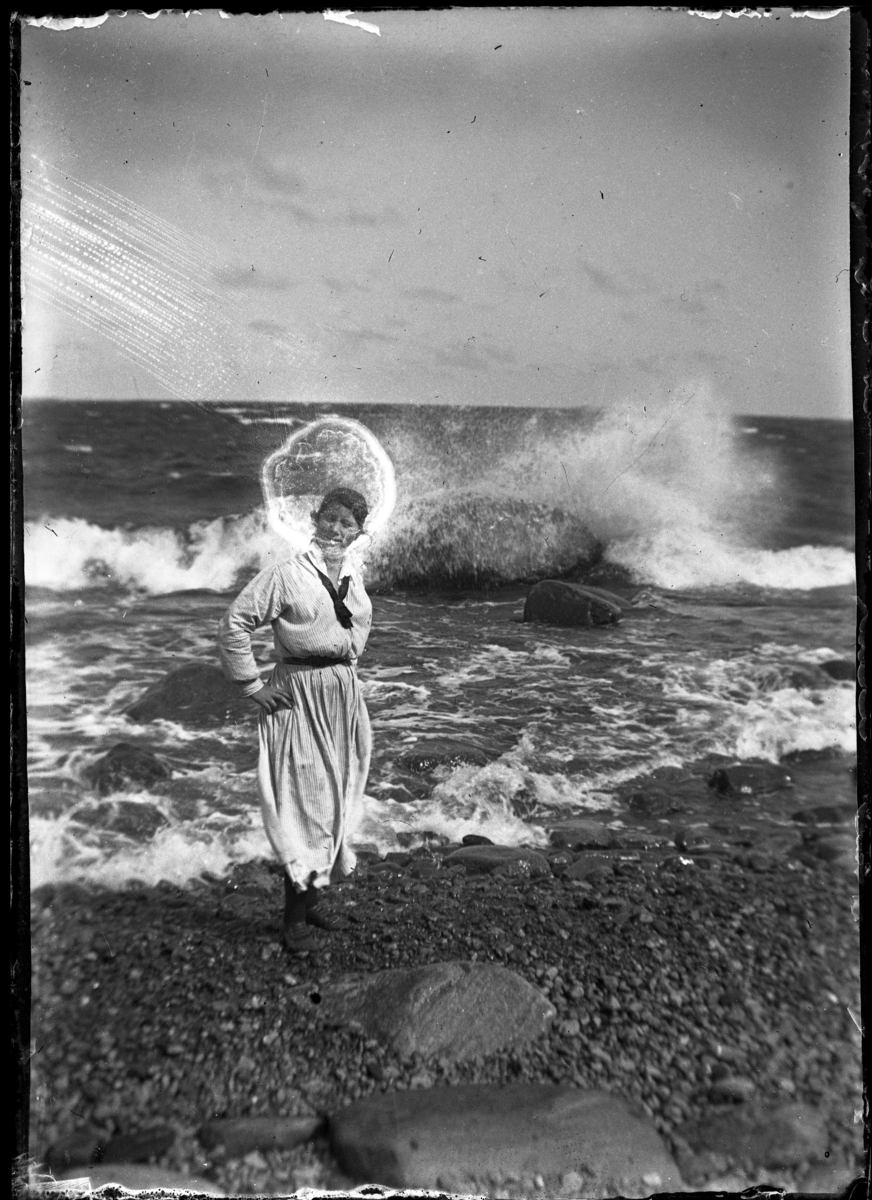 En kvinna står på stranden.
