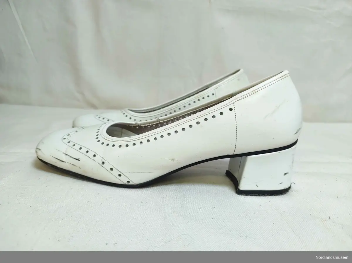 Hvite pensko til dame i skinn. Hullmønster. Noe høyde på hælene. I antatt uoriginal skoeske, da esken er har påskriften "Fine Line Romantique".