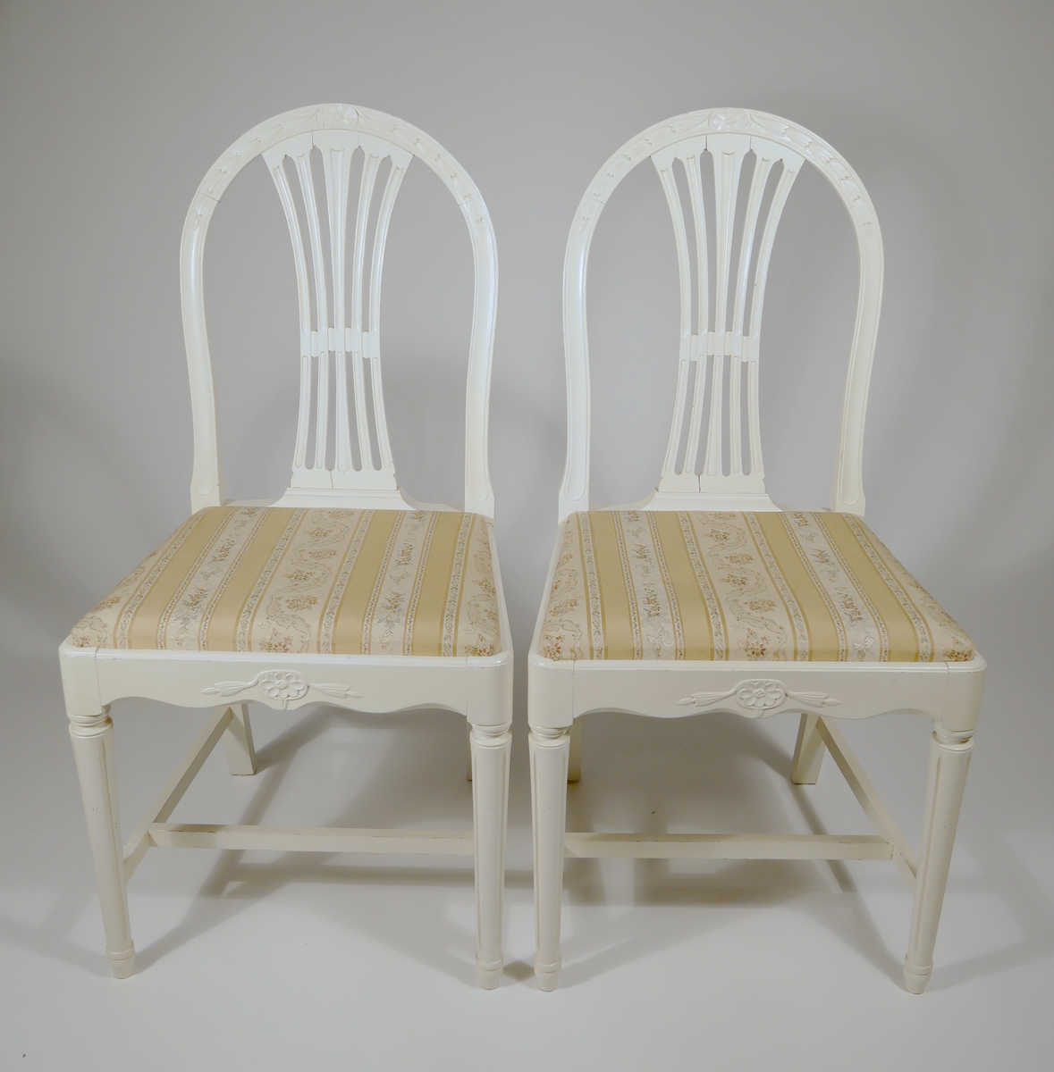 Två vitmålade stolar med löstagbar klädd sits. Märkta J.G.A. = J.G. Axelssons snickeriverkstad. Verkstaden tillverkade möbler på beställning och efter kundens önskemål.