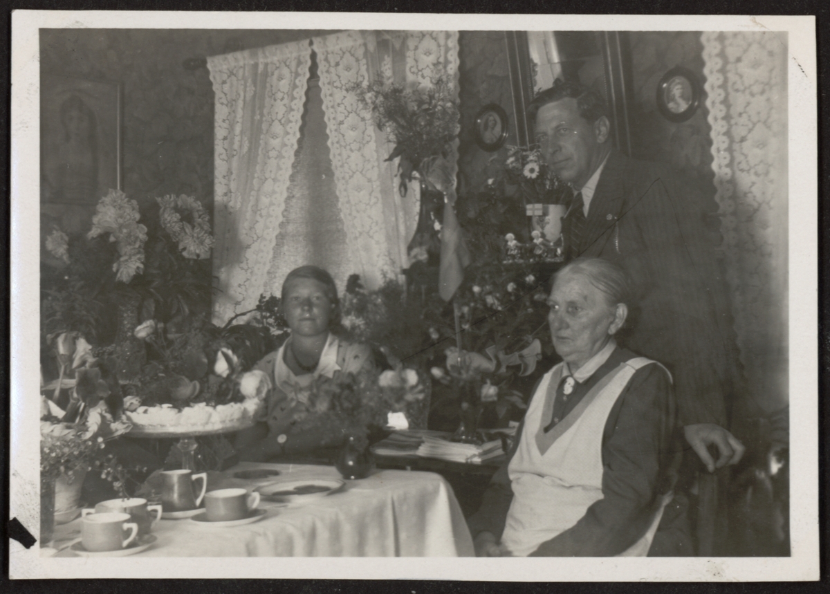 Bilden visar Hanna och Hugo Friberg vid ett kaffebord med en tårta och många blommor.