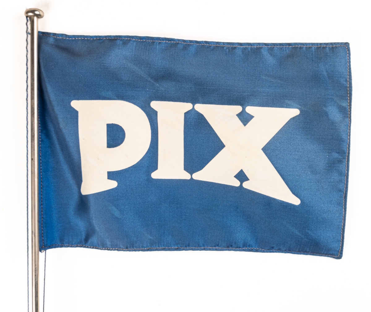 Bordsstandar i metall, blå och vit flagga med text: PIX.