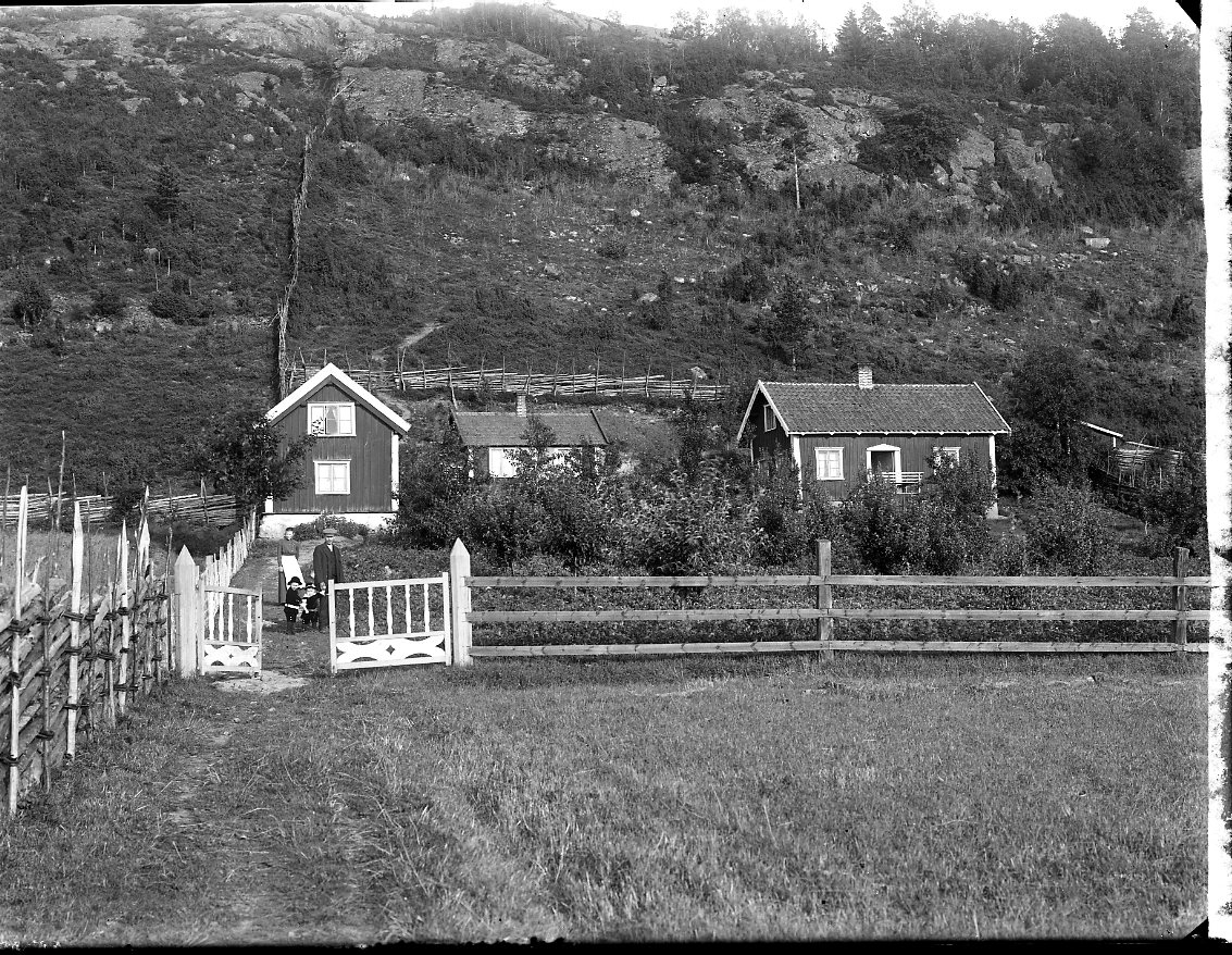 En gård vid Grännabergets fot i Uppgränna. Familjen Blom står innanför grinden.