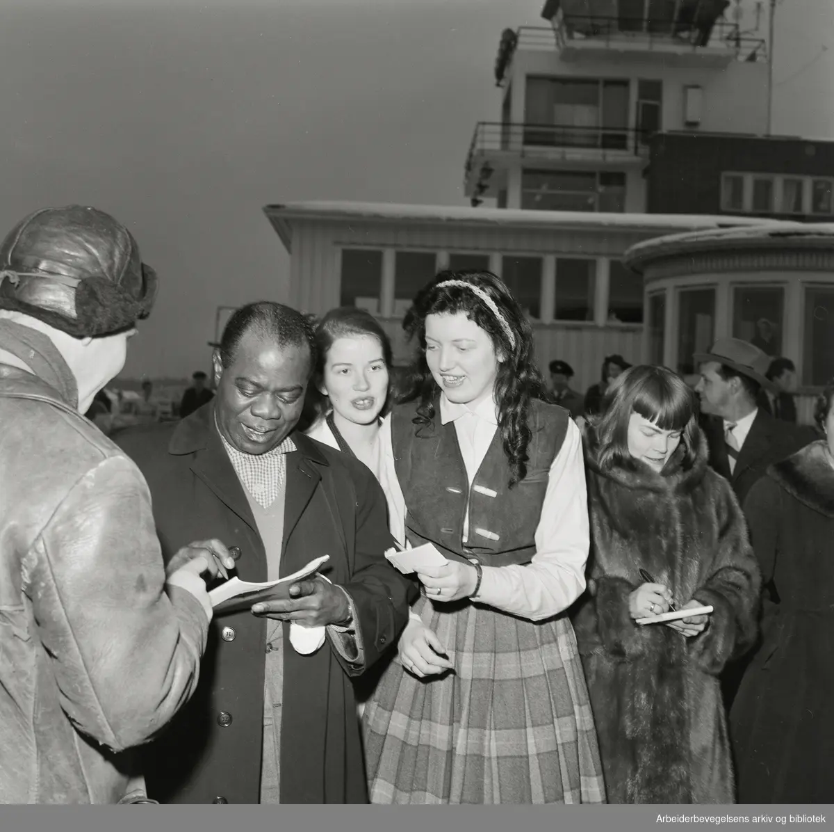 Louis Armstrong ankommer Oslo via Fornebu flyplass 2 februar 1959. Unge autografjegere.