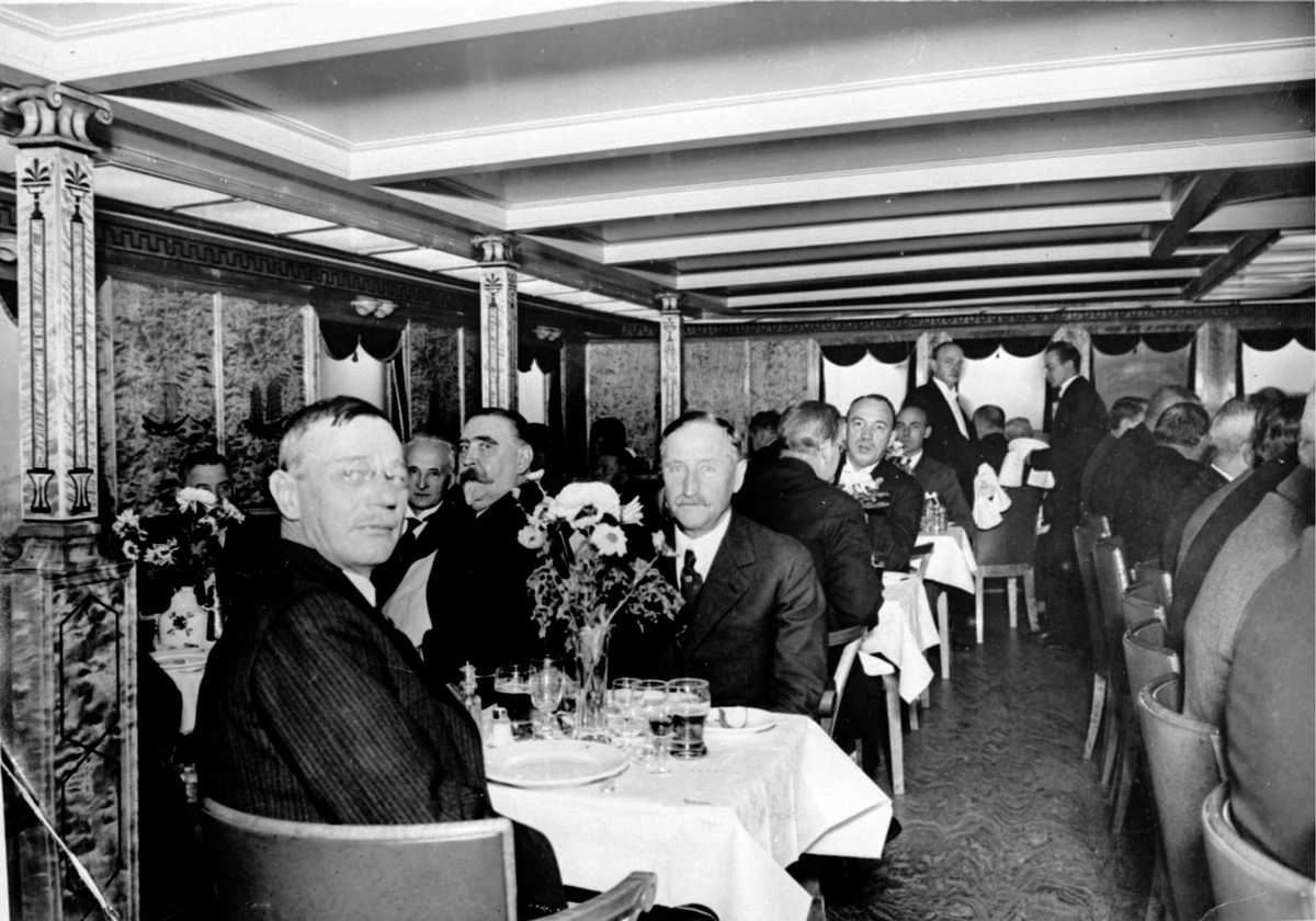 Passasjerer i spisesalongen ombord i hurtigruteskipet DS Prinsesse Ragnhild (1931). Bildet er tatt aktenfra på babord side