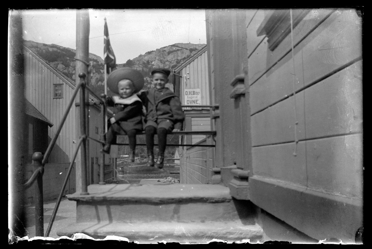 To gutter sitter på benken utenfor inngangen til Strandgaten 70 i Egersund