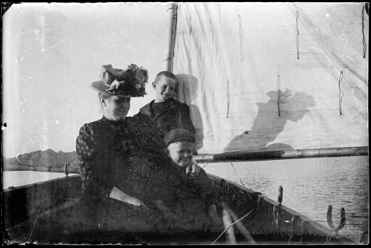 Kvinne og to barn i en seilbåt