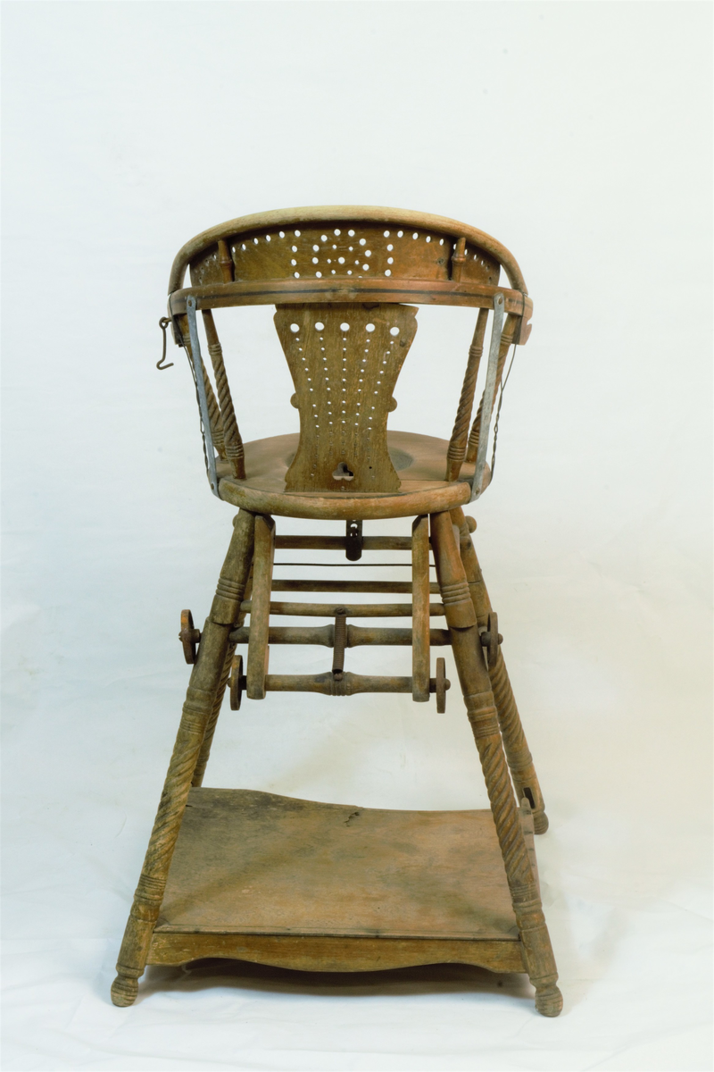 Barnestol med to funksjoner i en, siden den kan brettes ned til en liten lekestol med bord. Påfestede hjul som kan brukes til å trille den rundt når den er nedbrettet. Armlenene har på et tidspunkt blitt forsterket med metallstenger og metaltråd.