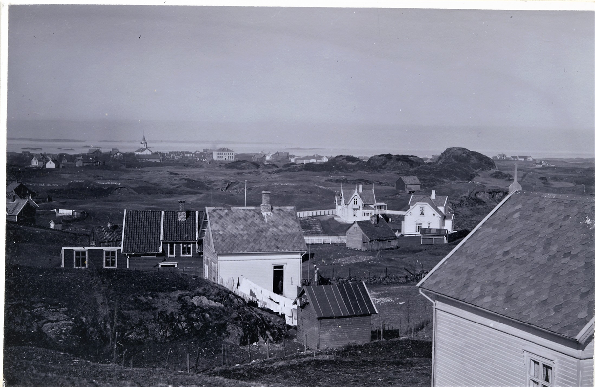Haugesund sett fra øst-sørøst. Skåre kirke og Hauge skole ses i bakgrunnen. I forgrunnen er spredt bebyggelse. En klesvask henger midt i bildet.
